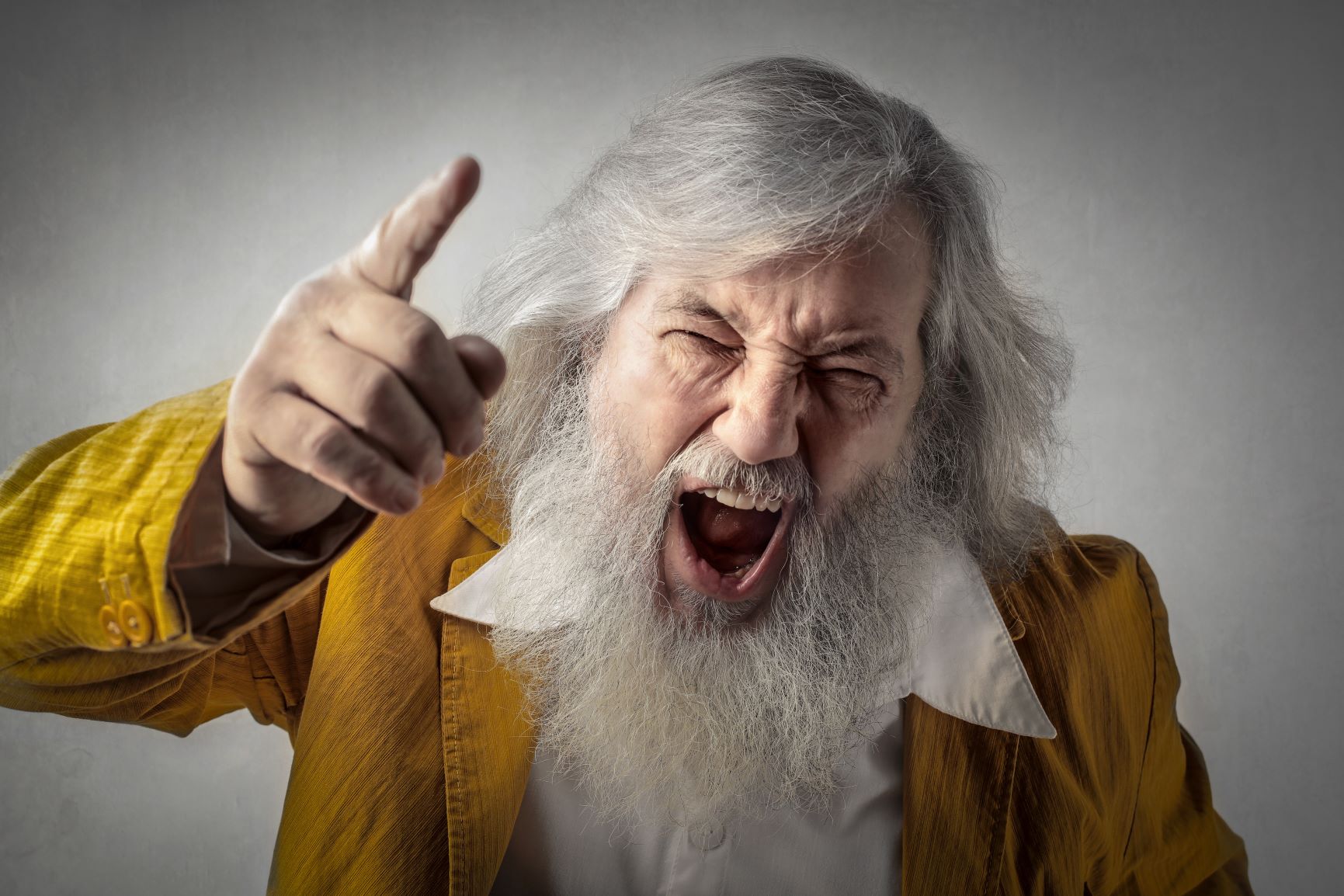 A man with long white hair and beard is pointing.