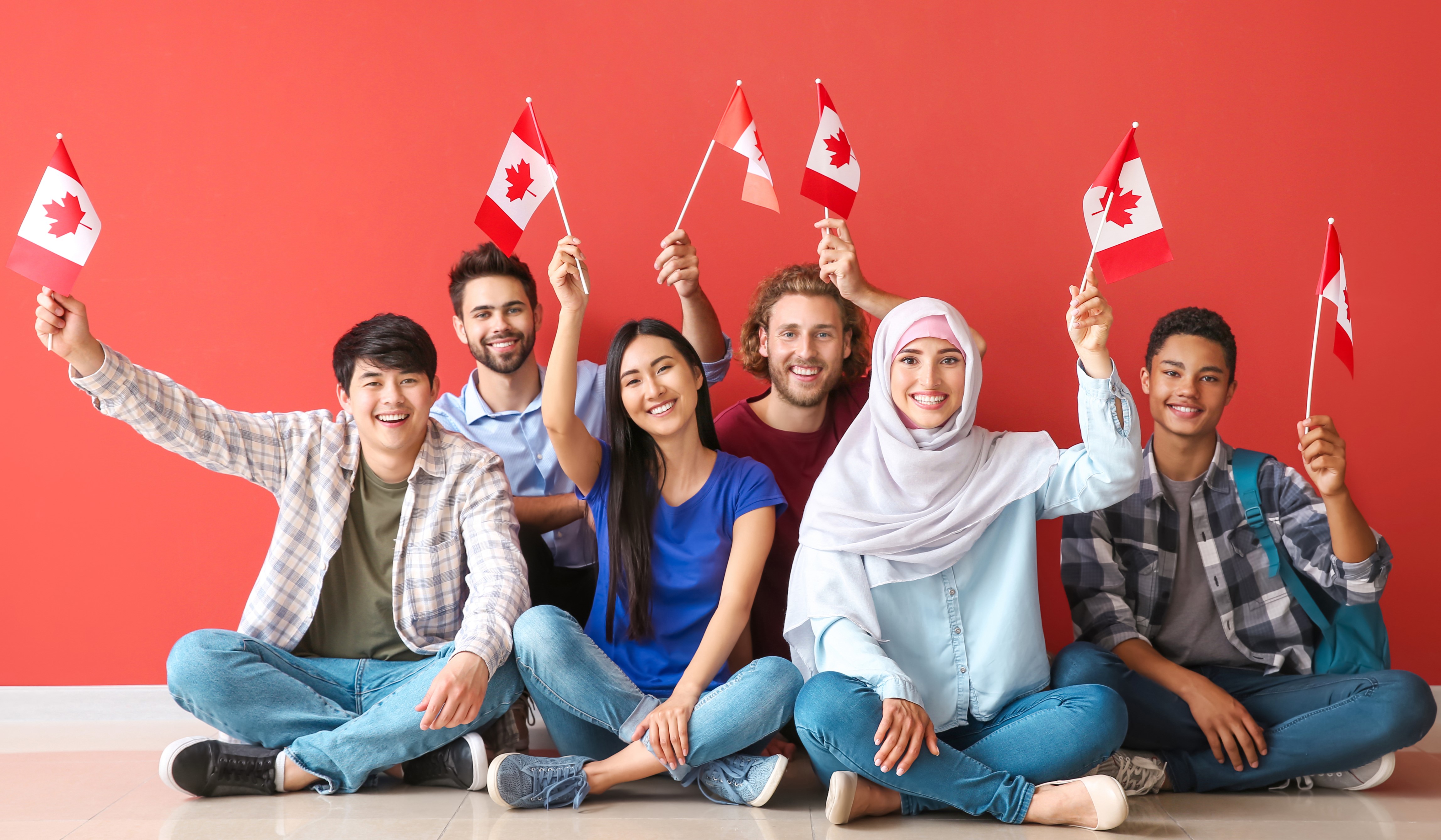 A group of people sitting on the ground holding canadian flags.