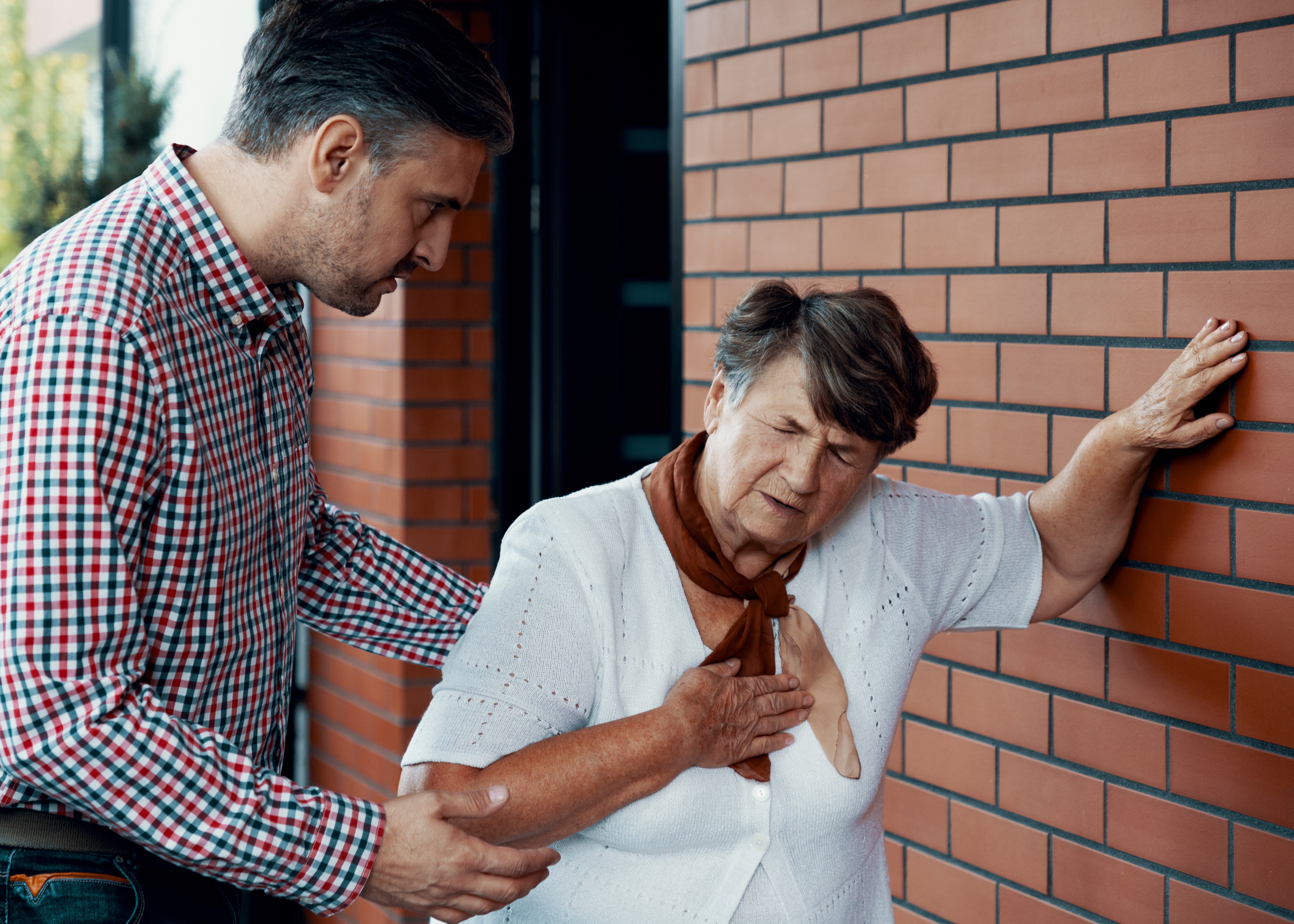 A man helping an older woman tie her neck tie.