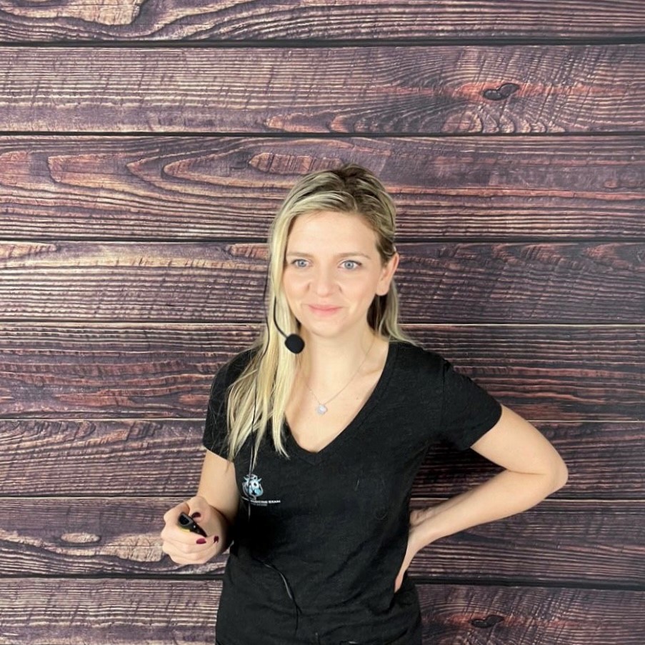 A woman standing in front of a wooden wall holding a wine glass.