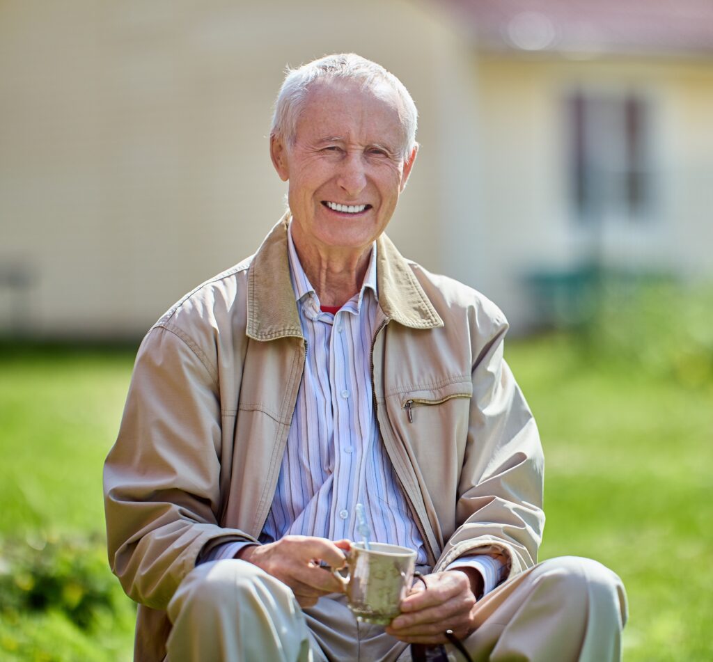 A man sitting on the ground holding a cup.