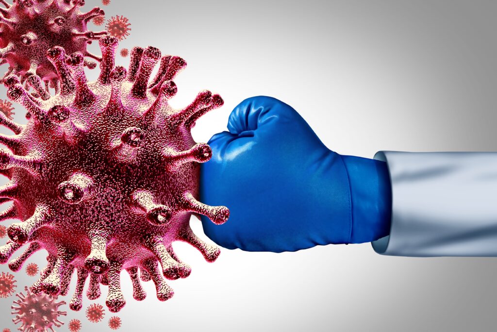 A person wearing boxing gloves and holding their fist up to the side of a virus.